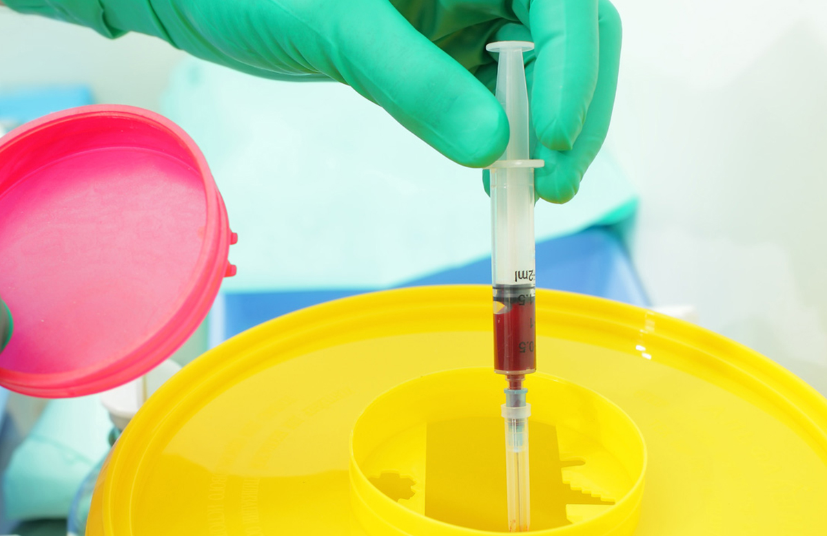 Healthcare Worker Disposing of Used Needlestick into Sharps Container